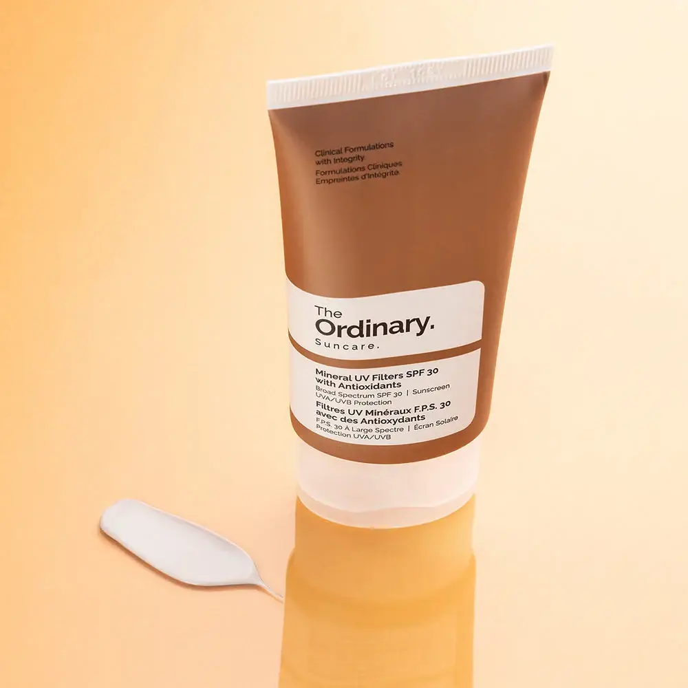 The Ordinary SPF 30 sunscreen on warm background with swatch